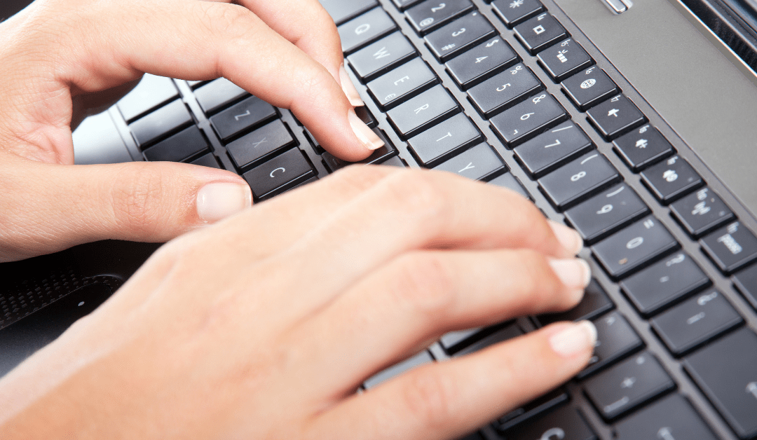 mão digitando em um teclado de computador buscando uma vaga temporária de emprego